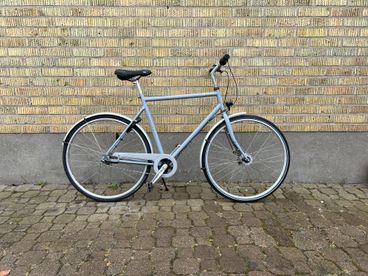 A silver bicycle standing against a yellow brick wall
